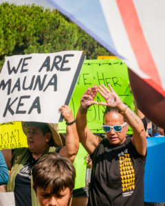 protestor carrying a sign that reads "we are mauna kea"